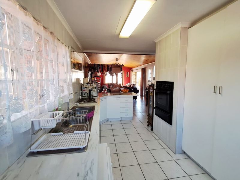 Open plan kitchen featuring tiled flooring, built-in oven, hob, and ample cabinetry, flowing into the adjacent living area.