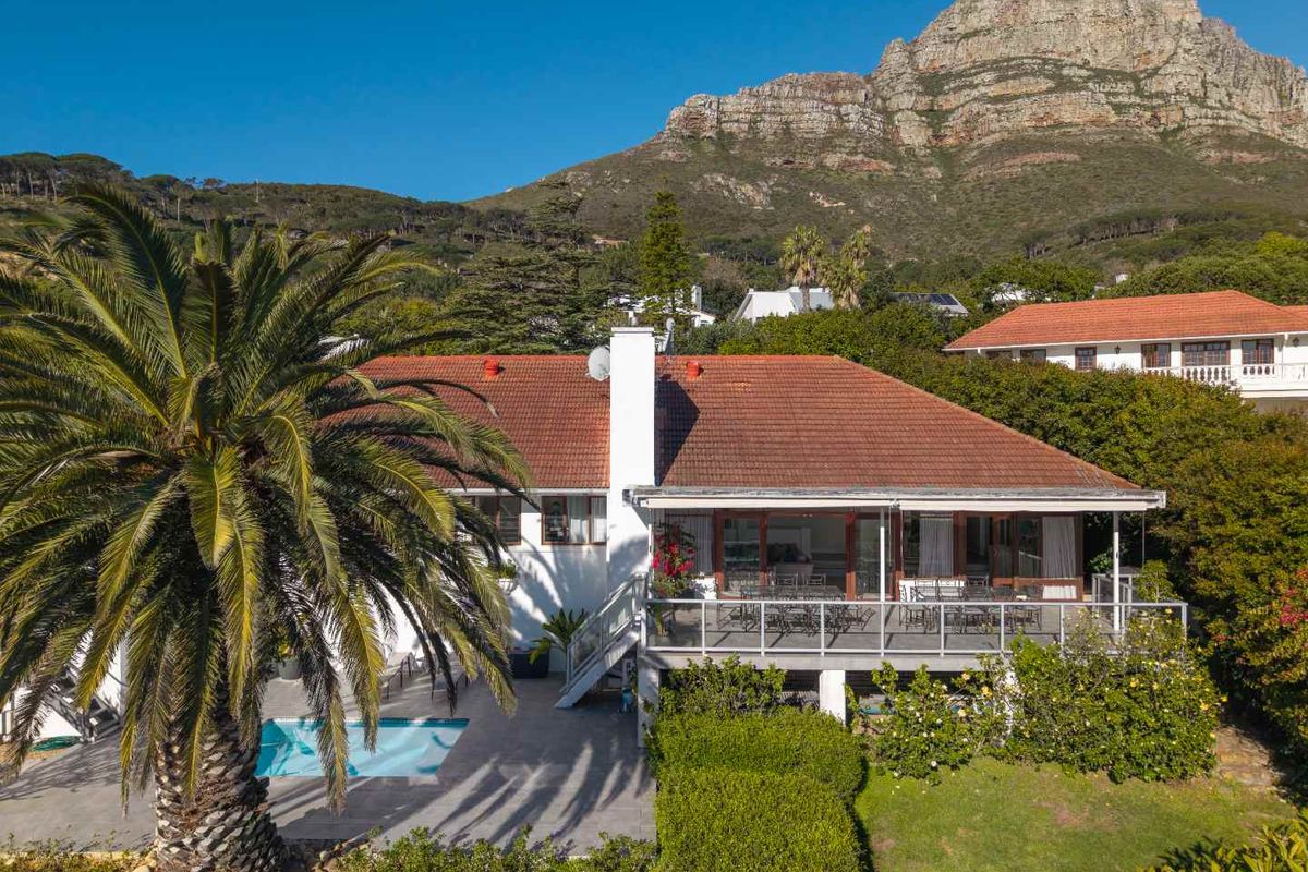 Rear view of the house featuring a raised deck, swimming pool, and mountain backdrop.