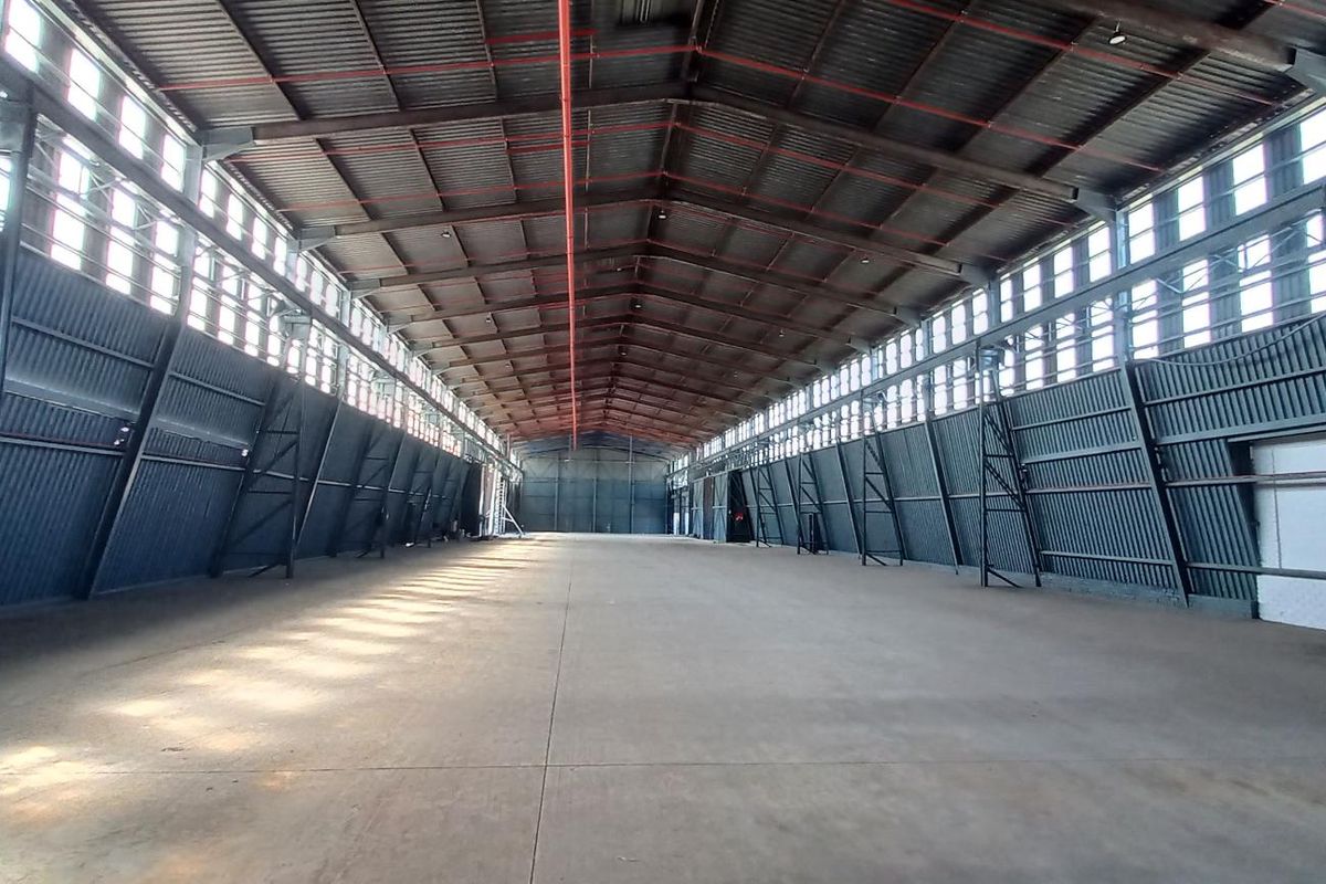 Spacious industrial warehouse featuring a high-clearance steel portal frame, concrete flooring, fire sprinkler system, and extensive natural light from clerestory windows.