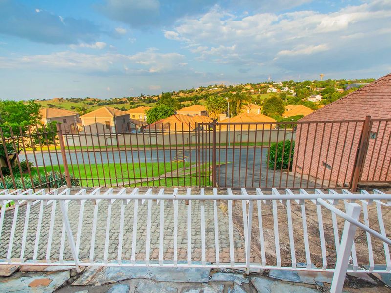 An elevated balcony area featuring stone paving and metal railings, offering an expansive view over the surrounding residential neighbourhood.