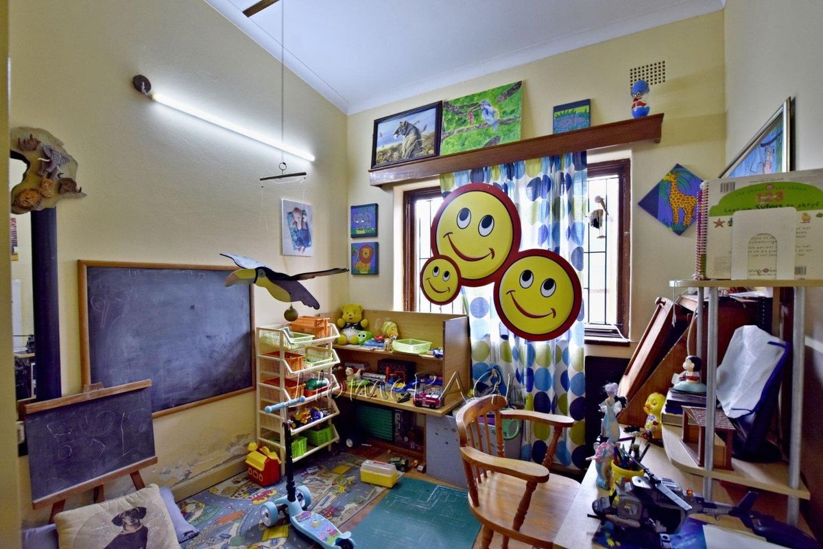 A bedroom space currently utilized as a playroom, featuring a window with security bars and built-in wall lighting.