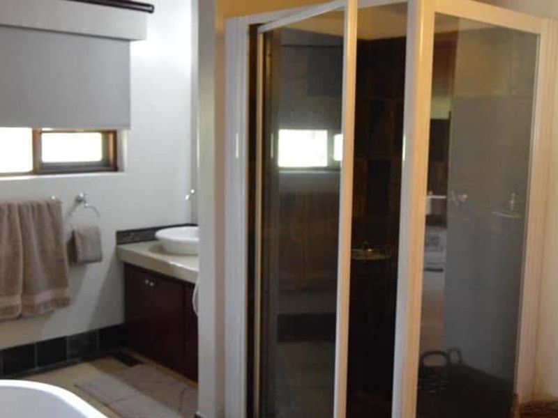 A bathroom featuring a freestanding bathtub, a separate shower enclosure, a vanity with a vessel sink, and a rustic exposed timber beam ceiling.