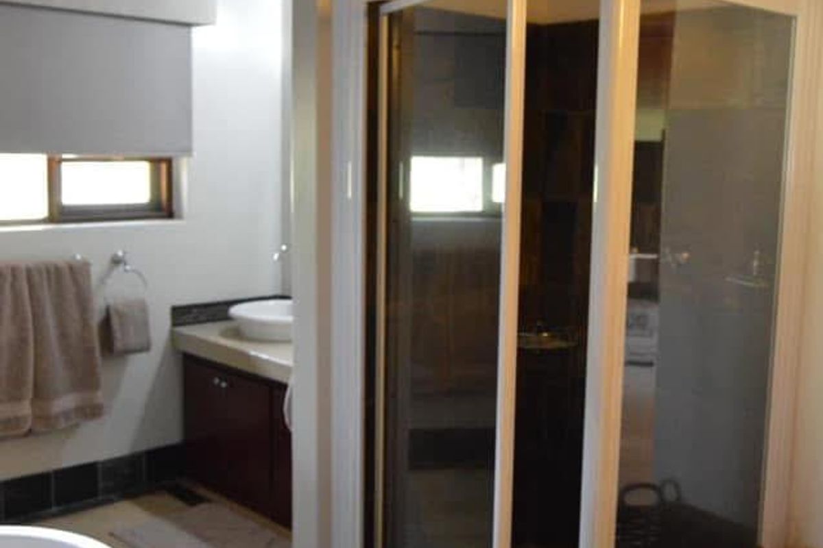 A bathroom featuring a freestanding bathtub, a separate shower enclosure, a vanity with a vessel sink, and a rustic exposed timber beam ceiling.