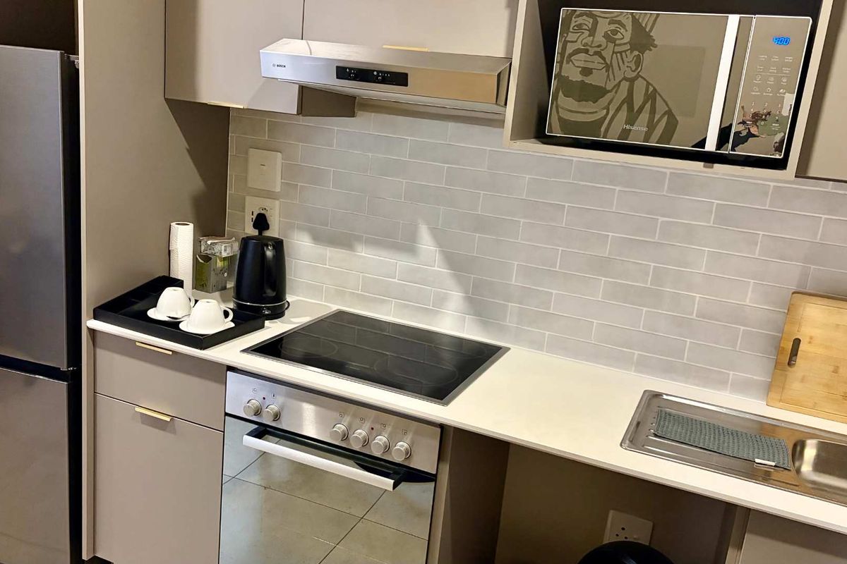 Modern kitchen featuring sleek cabinetry, subway tile backsplash, integrated appliances including an oven and hob, and a contemporary brass faucet.