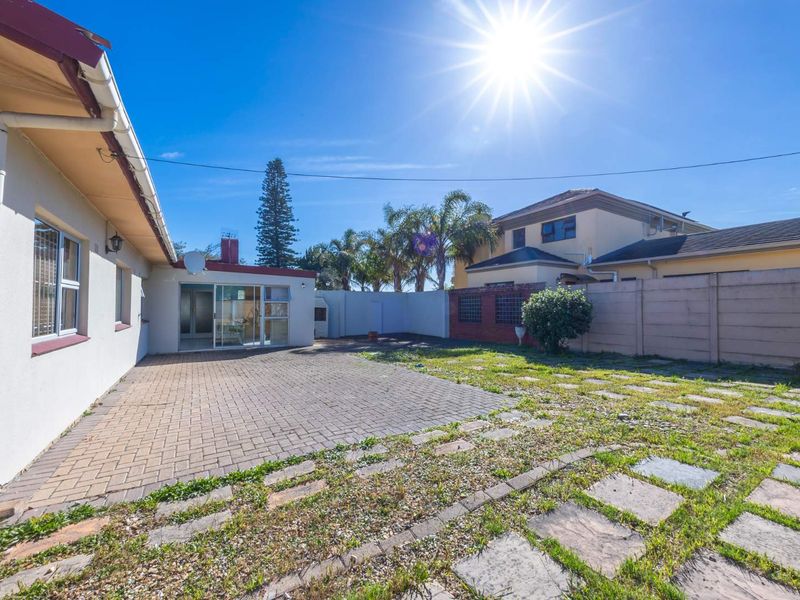 Rear exterior view featuring a paved patio area, boundary wall, and access to the home via a sliding glass door.