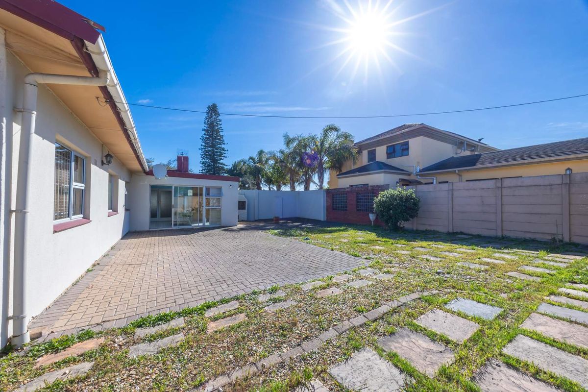 Rear exterior view featuring a paved patio area, boundary wall, and access to the home via a sliding glass door.