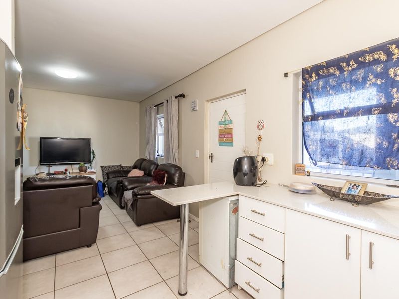 Open-plan living area featuring tiled flooring and a functional kitchen with stone countertops and a breakfast bar.