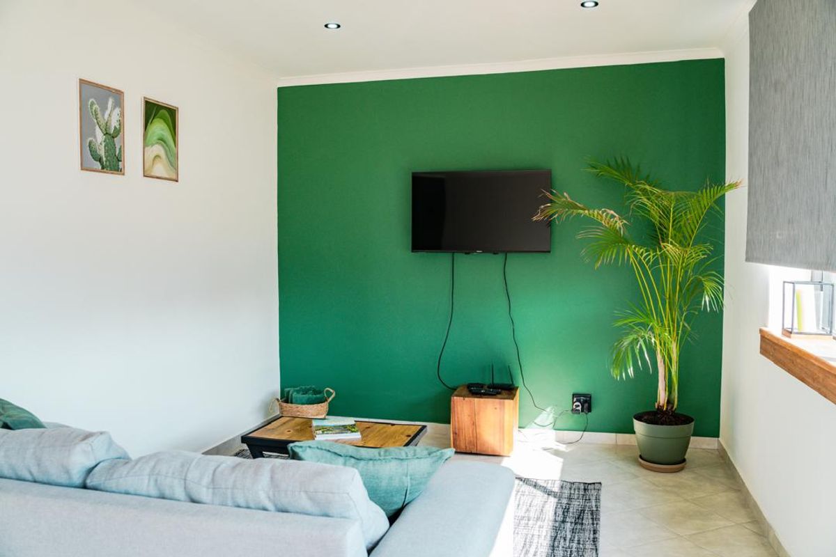 A bright living room featuring a bold green accent wall, tiled flooring, and recessed ceiling lighting.