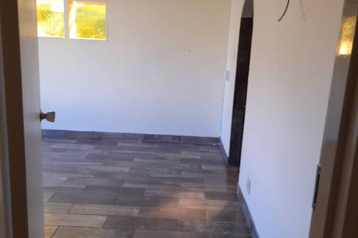 An empty room featuring wood-look tile flooring, an arched doorway, and neutral wall finishes, ready for personalization.