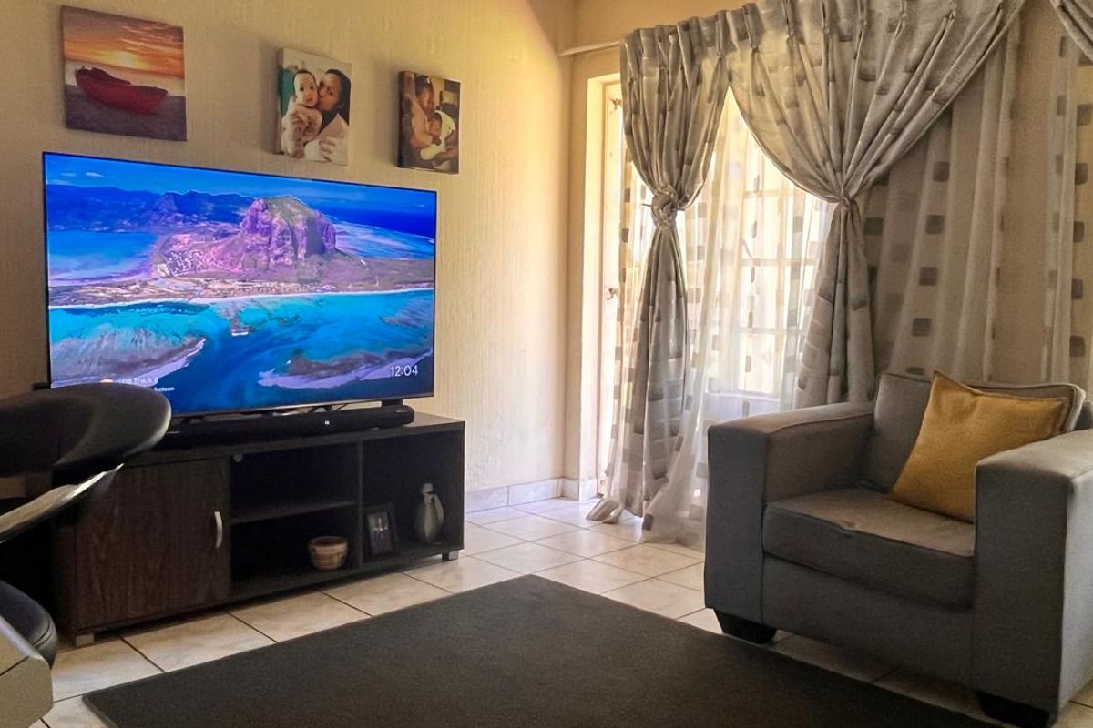 A comfortable living room featuring tiled flooring and a glass sliding door that provides access to the exterior.