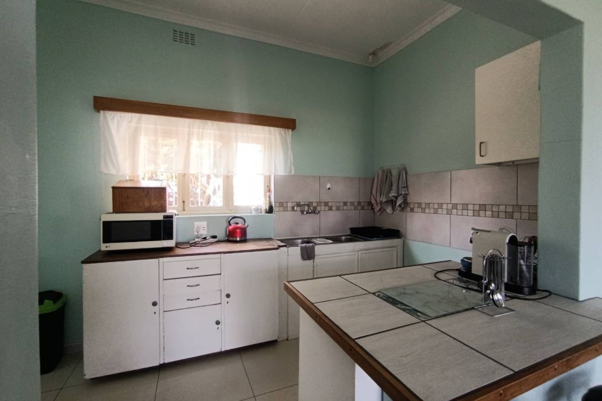 A functional kitchen featuring tiled countertops, built-in cabinetry, and a double sink, offering a practical layout with potential for modern updates.