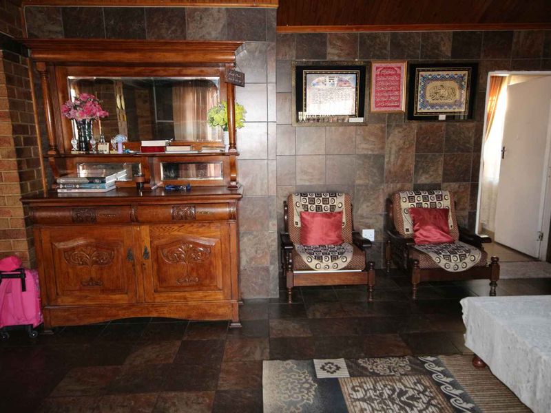 A living area featuring dark tiled flooring and matching wall cladding, providing a distinct, traditional aesthetic.