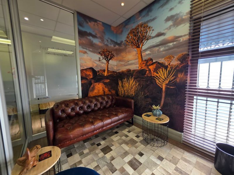 A professional office space featuring a glass partition wall, recessed lighting, and a large landscape mural wall feature.