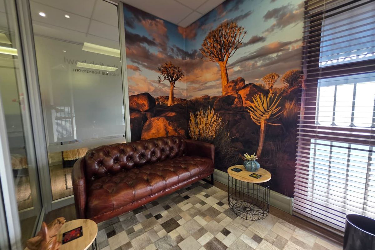 A professional office space featuring a glass partition wall, recessed lighting, and a large landscape mural wall feature.