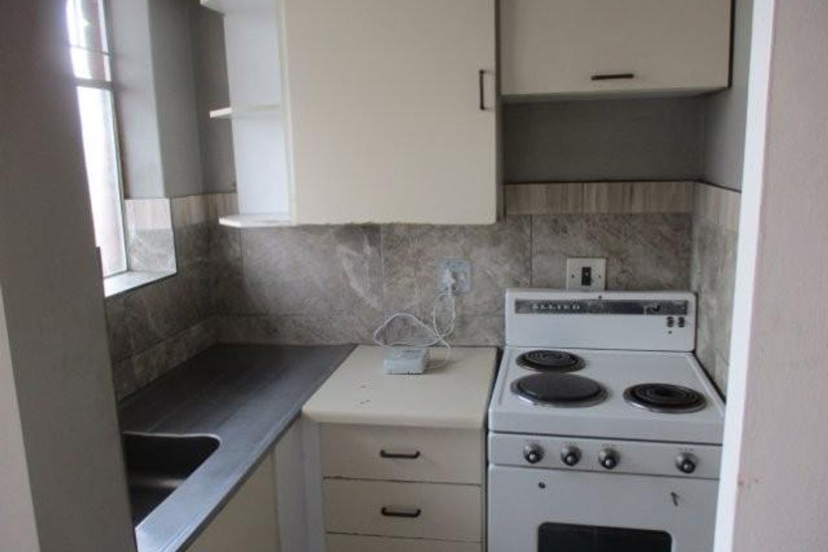Compact kitchen featuring built-in cabinetry, a tiled backsplash, and a freestanding electric stove, offering a functional layout ready for modernization.