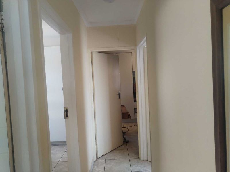 A functional hallway featuring tiled flooring and access to multiple rooms, presenting a neutral canvas for interior updates.