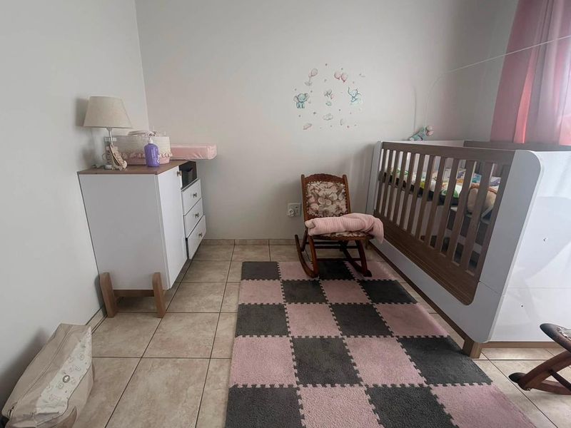 A nursery bedroom featuring neutral wall finishes and tiled flooring, providing a functional space for a child's room.