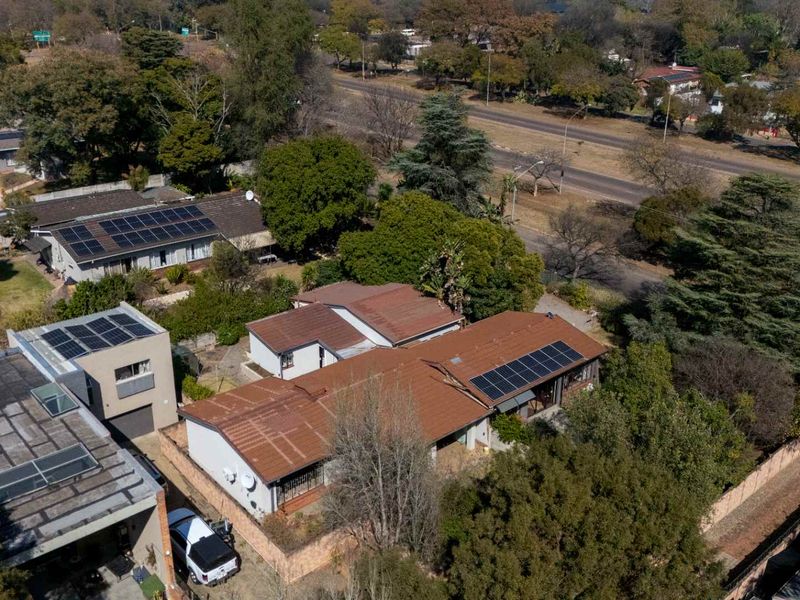 Aerial view of the property showcasing the roof structure, installed solar panels, and surrounding residential grounds.
