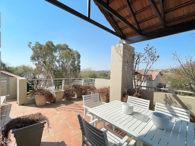 Spacious covered balcony featuring tiled flooring, concrete pillars, and metal railings, offering an open-air outdoor living space with neighborhood views.
