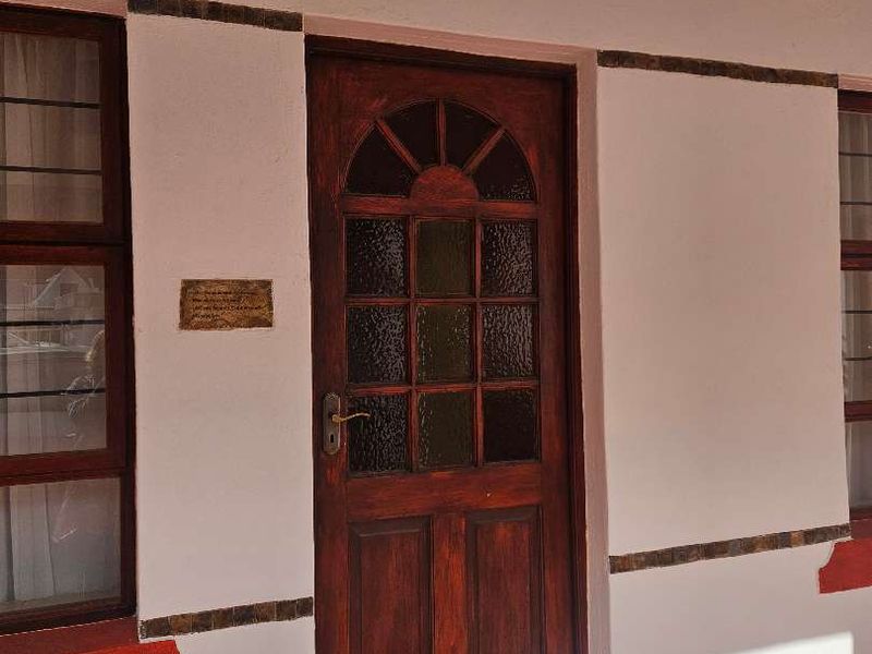 Entrance area featuring a timber front door with glass panels, tiled patio flooring, and decorative wall accents.