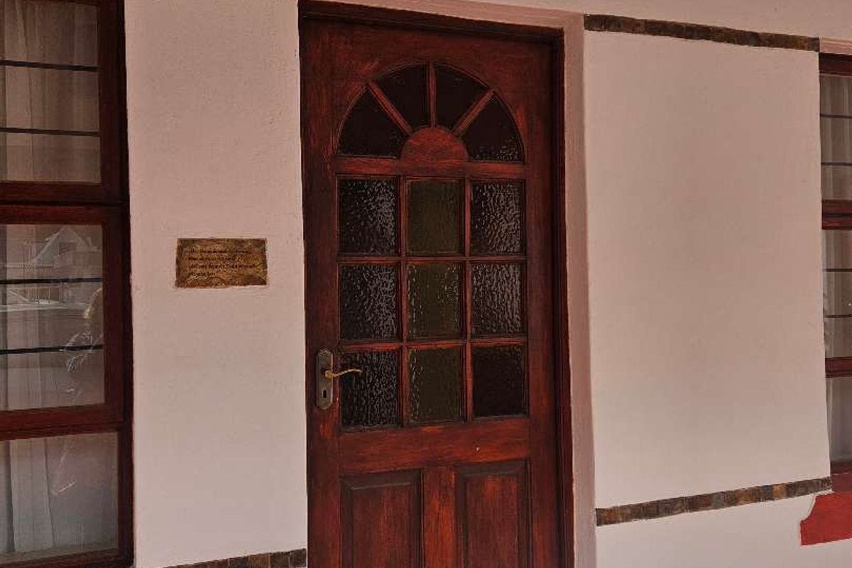 Entrance area featuring a timber front door with glass panels, tiled patio flooring, and decorative wall accents.