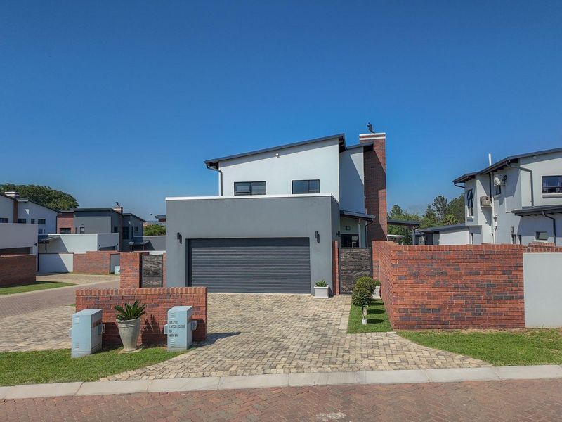 Modern double-storey residential home featuring a brick and rendered facade, paved driveway, and integrated double garage within a secure estate setting.
