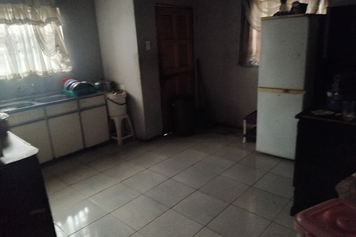 A dated kitchen featuring tiled flooring, basic cabinetry, and a double sink, requiring modernization to improve functionality and aesthetic appeal.