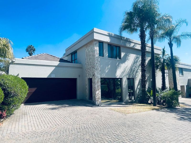 Modern double-story townhouse exterior featuring a paved driveway, double garage, and attractive stone cladding detail on the facade.