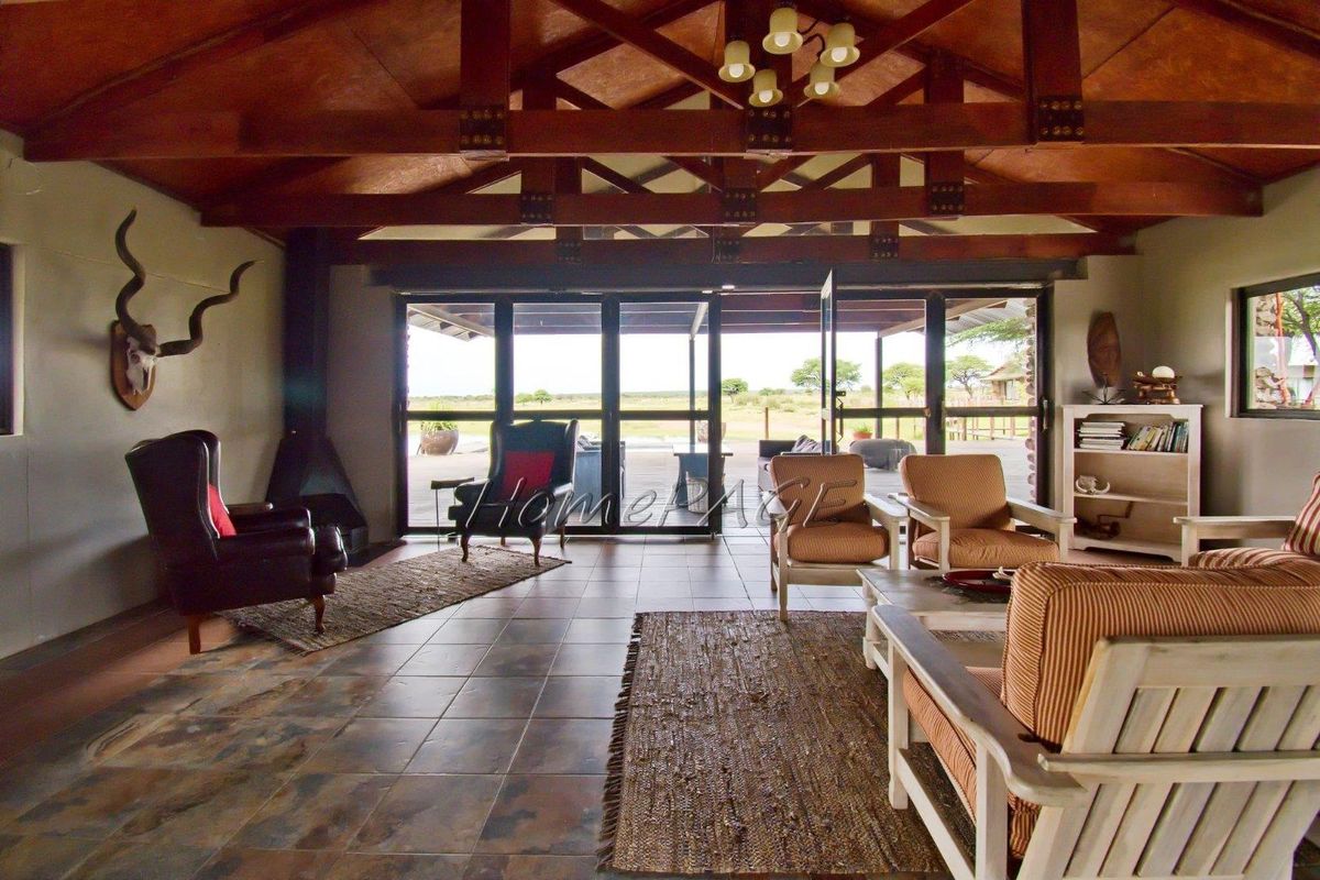 Spacious living area featuring exposed timber roof trusses, tiled flooring, and large glass sliding doors opening onto a covered patio with landscape views.