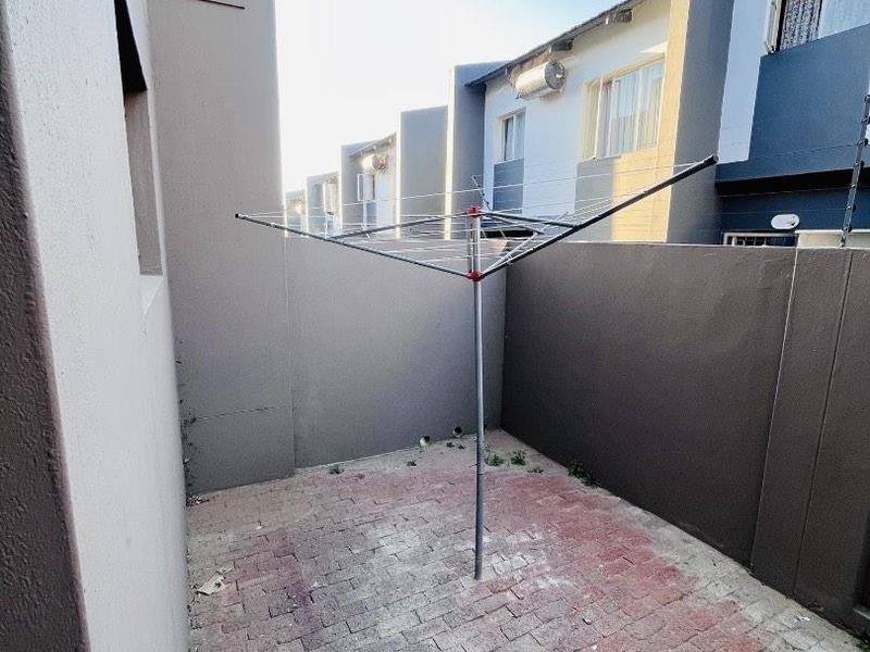 A private rear courtyard featuring paved flooring and high boundary walls with integrated electric fencing, providing a secure and functional outdoor utility space.