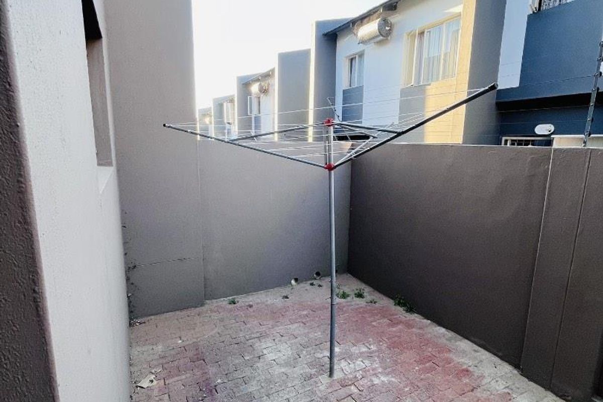 A private rear courtyard featuring paved flooring and high boundary walls with integrated electric fencing, providing a secure and functional outdoor utility space.