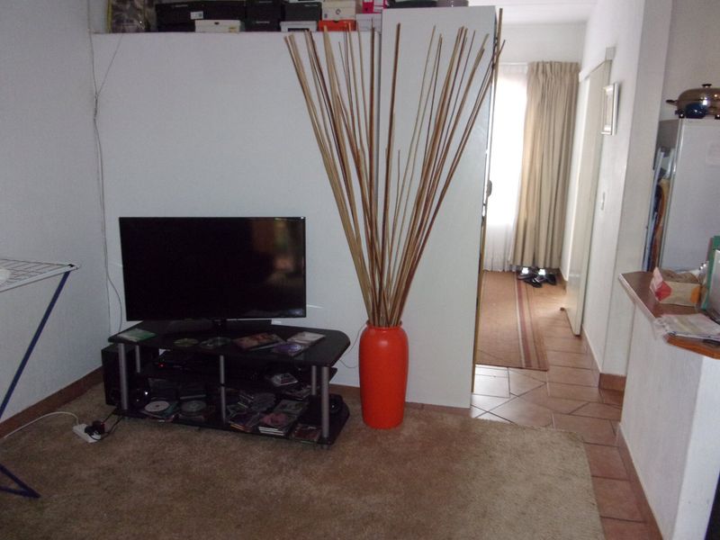 A living area featuring a mix of tiled and carpeted flooring, providing a functional space with direct access to an adjacent hallway.
