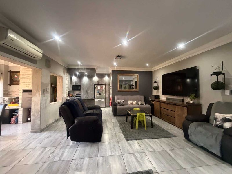 Spacious open-plan living area featuring tiled flooring, recessed lighting, a split-system air conditioner, and integrated kitchen cabinetry.