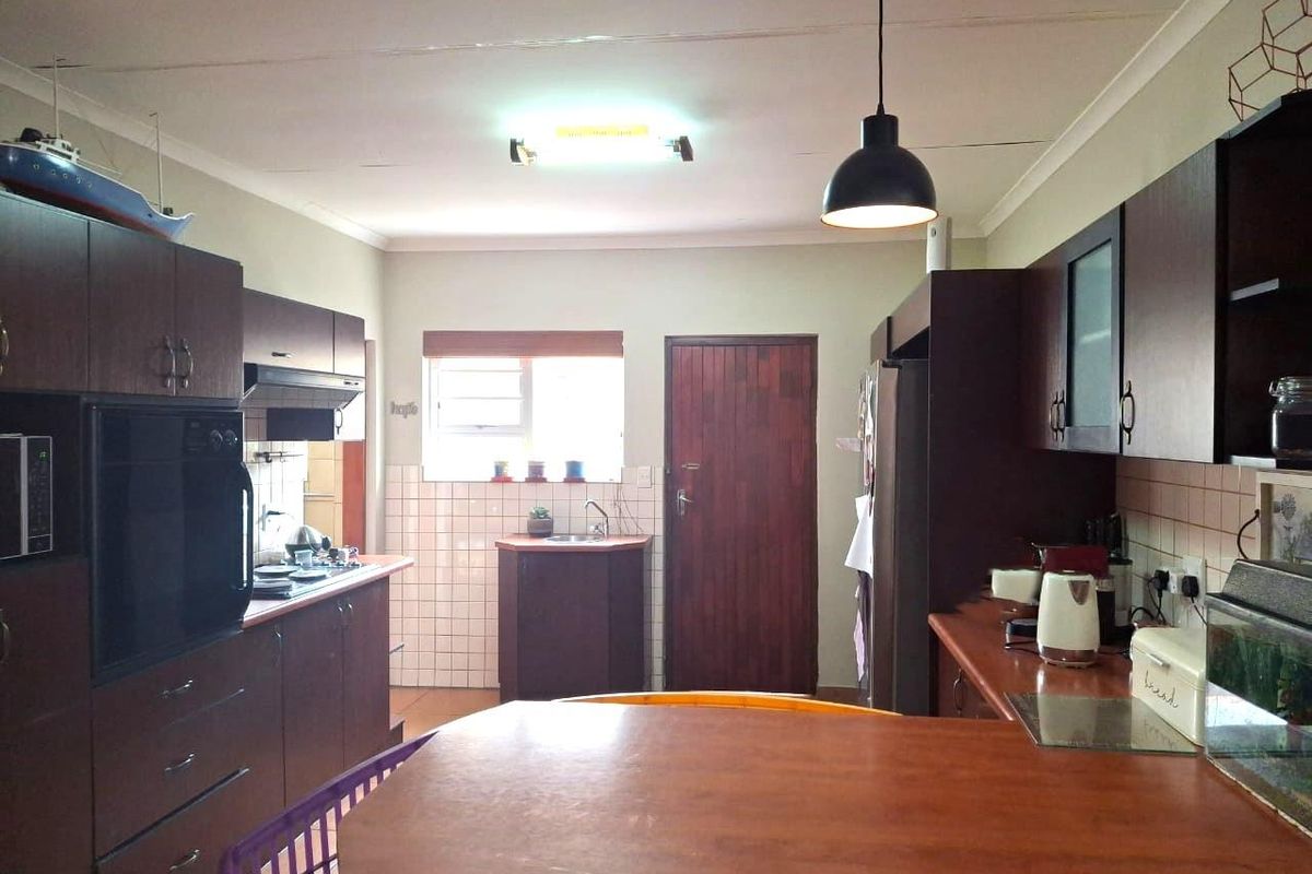 Functional kitchen featuring dark wood cabinetry, laminate countertops, built-in oven, extractor fan, and tiled backsplash with a practical layout.