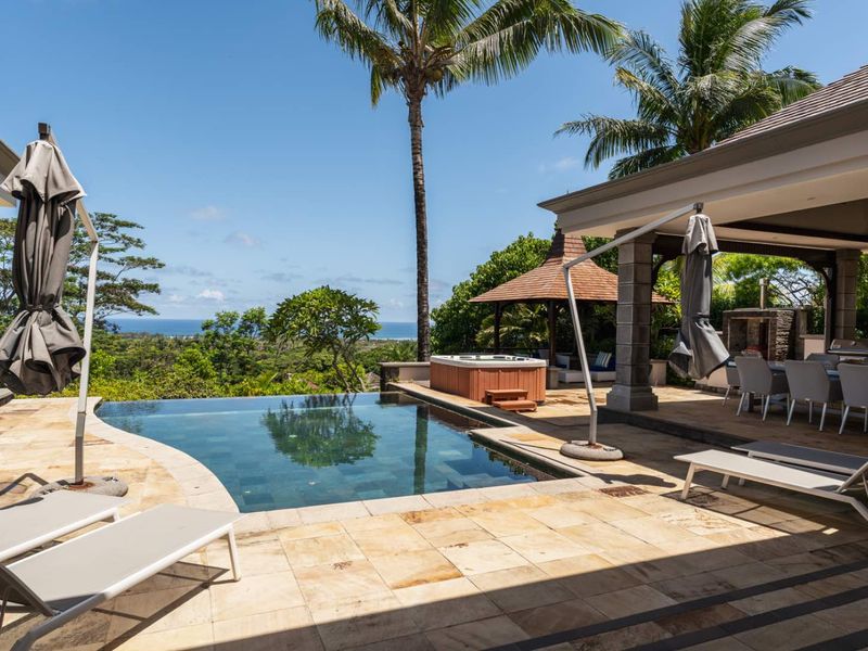 Outdoor entertainment area featuring an infinity-edge swimming pool, a built-in jacuzzi, a covered patio, and scenic ocean views.