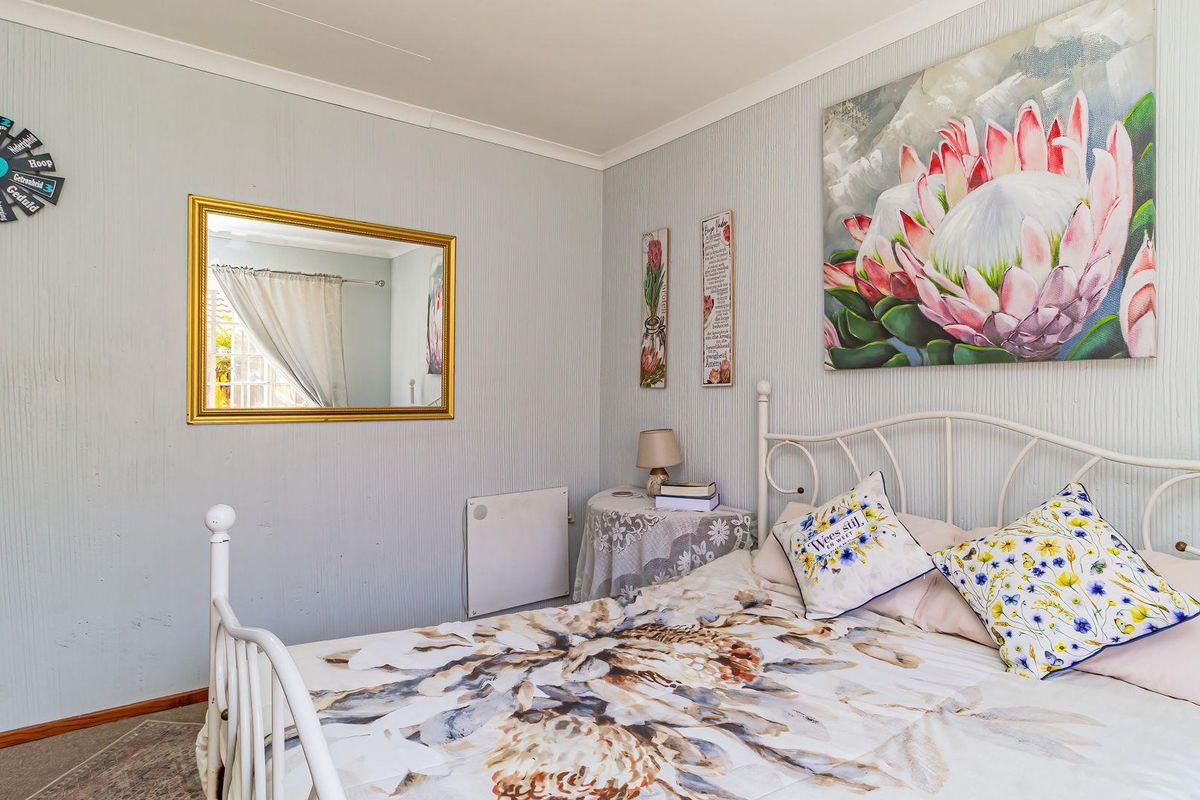 A cozy bedroom featuring textured wallpaper, coving, and a wall-mounted electric heater, providing a comfortable and functional living space.