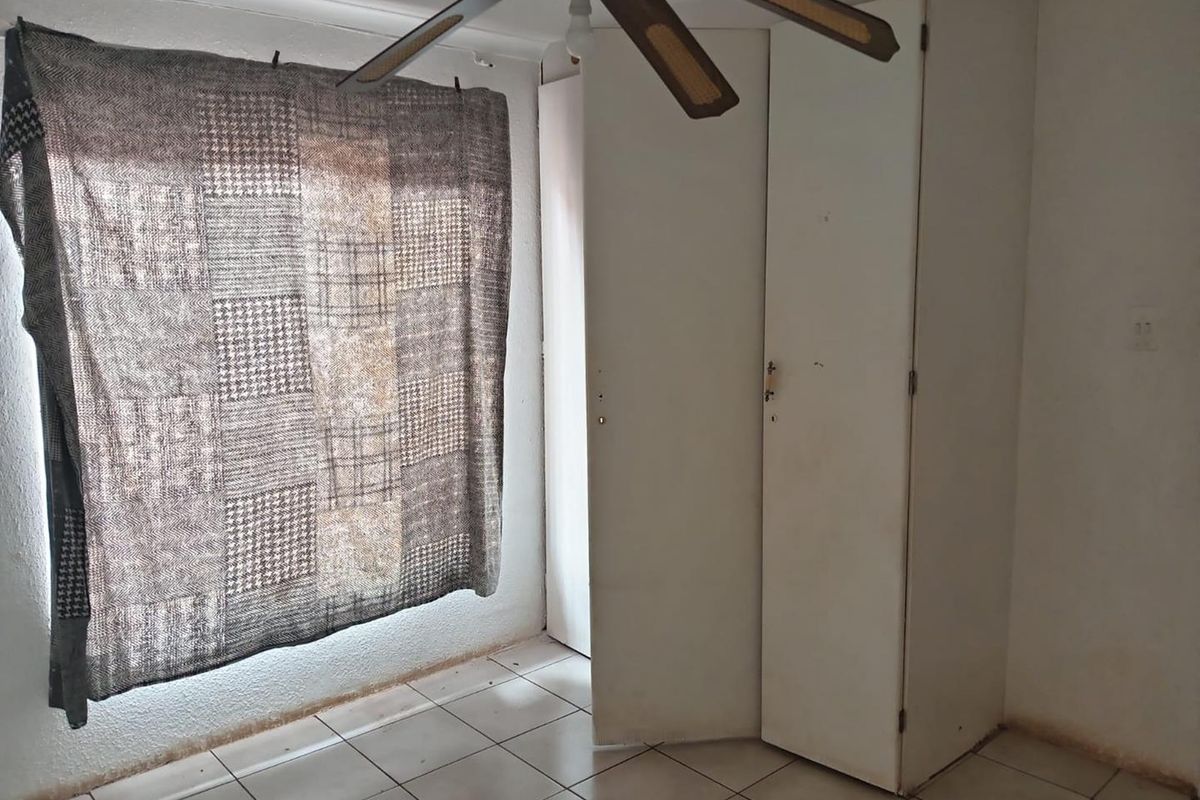A bedroom featuring tiled flooring, a ceiling fan, and built-in storage cupboards.