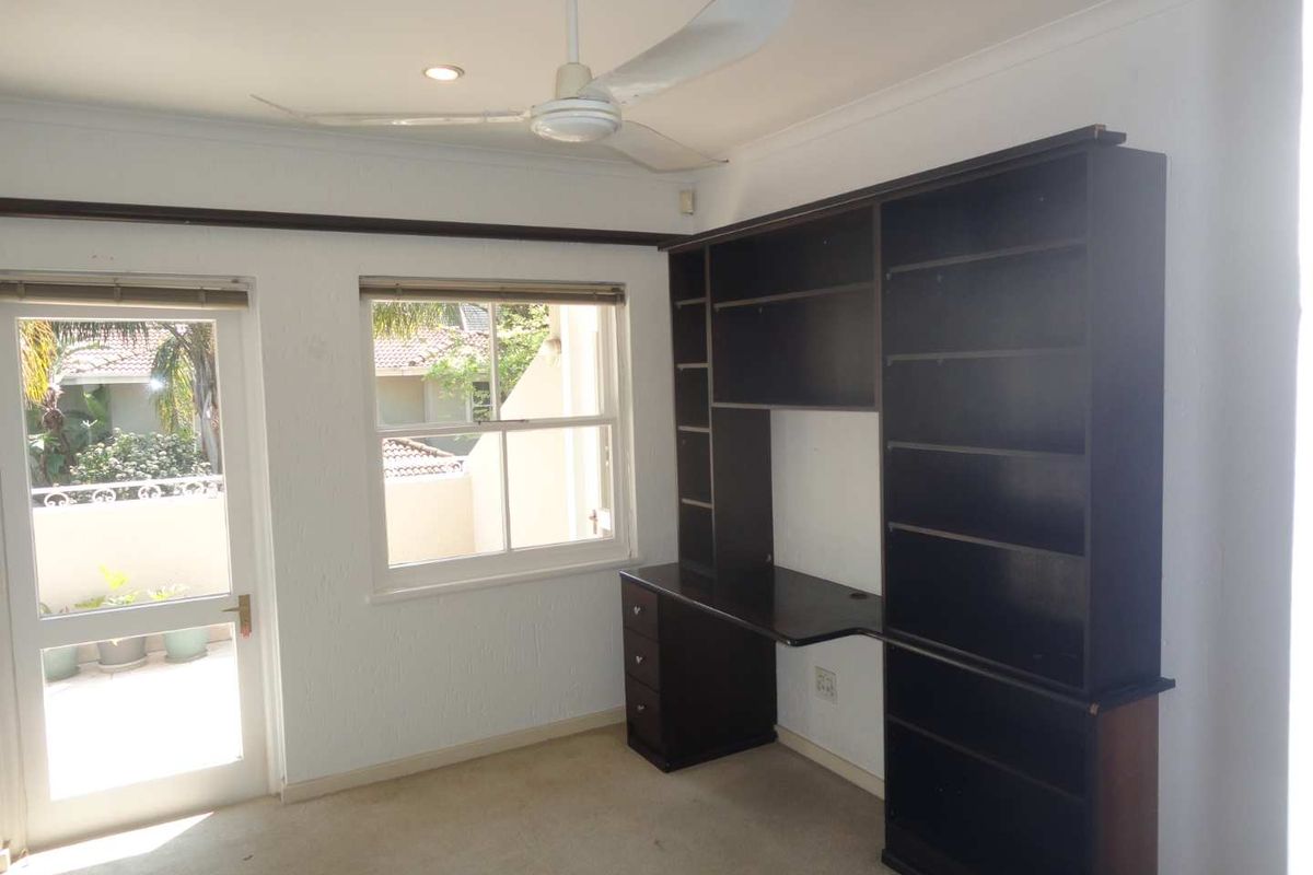 Bedroom featuring a built-in desk and shelving unit, ceiling fan, and direct access to an outdoor area through a glass panel door.