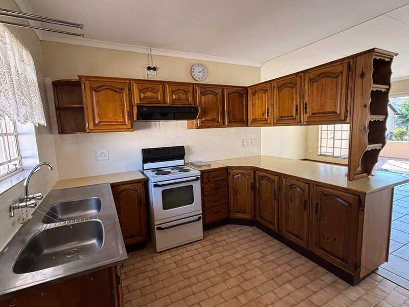 A functional kitchen featuring traditional wooden cabinetry, a double stainless steel sink, and a freestanding stove, offering a classic layout with ample storage space.