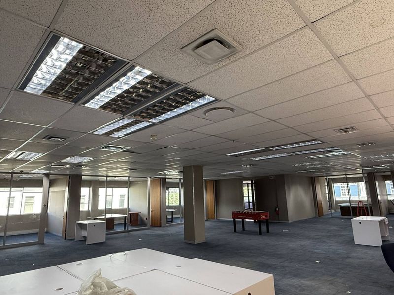 Spacious open-plan office area featuring suspended ceilings, recessed lighting, air conditioning, and glass partitioning, offering a versatile workspace layout.