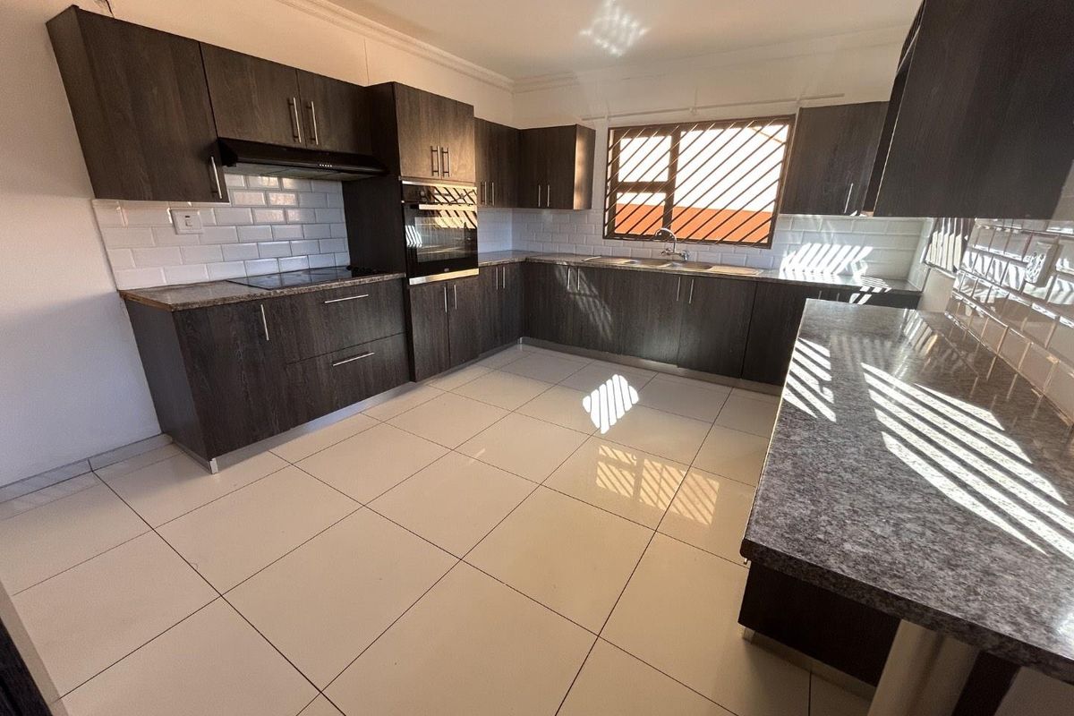 Modern kitchen featuring dark wood cabinetry, granite countertops, subway tile backsplash, built-in oven, and ceramic floor tiles.