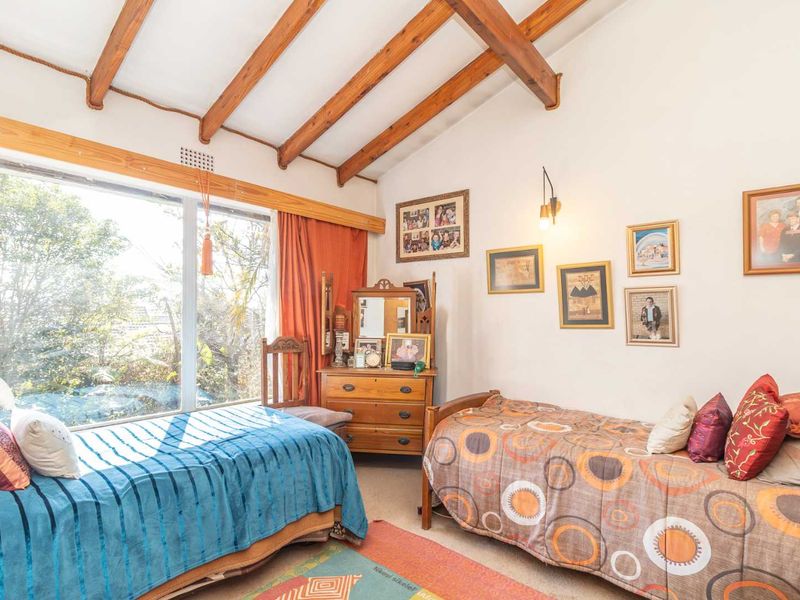 A bedroom featuring exposed timber ceiling beams and a large window providing natural light and garden views.