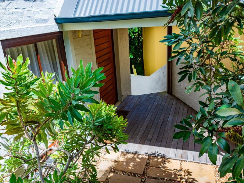A private rear entrance area featuring timber decking, stone pavers, and a sheltered walkway leading to a timber door.