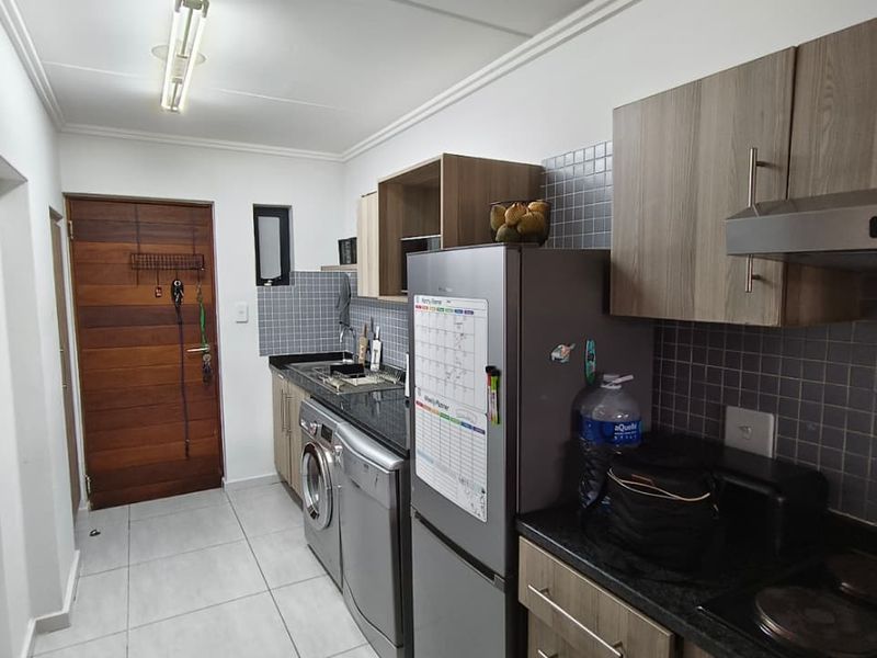 A functional kitchen featuring modern wood-finish cabinetry, granite countertops, tiled backsplash, and integrated appliances, providing a clean and practical workspace.