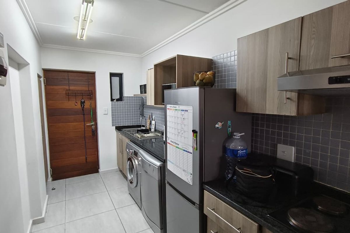 A functional kitchen featuring modern wood-finish cabinetry, granite countertops, tiled backsplash, and integrated appliances, providing a clean and practical workspace.