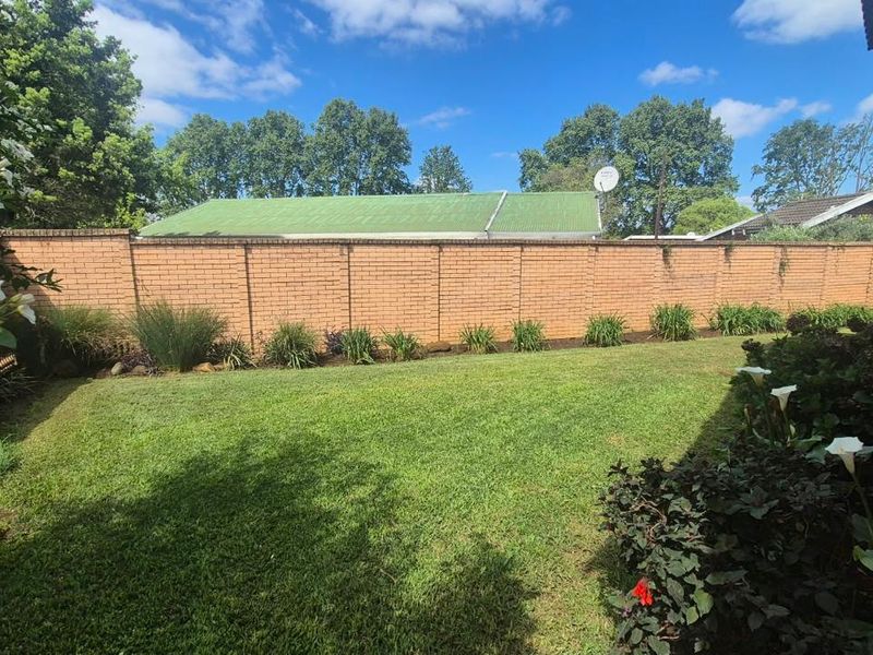 A well-maintained private rear garden featuring a lush green lawn and a solid brick boundary wall providing privacy.