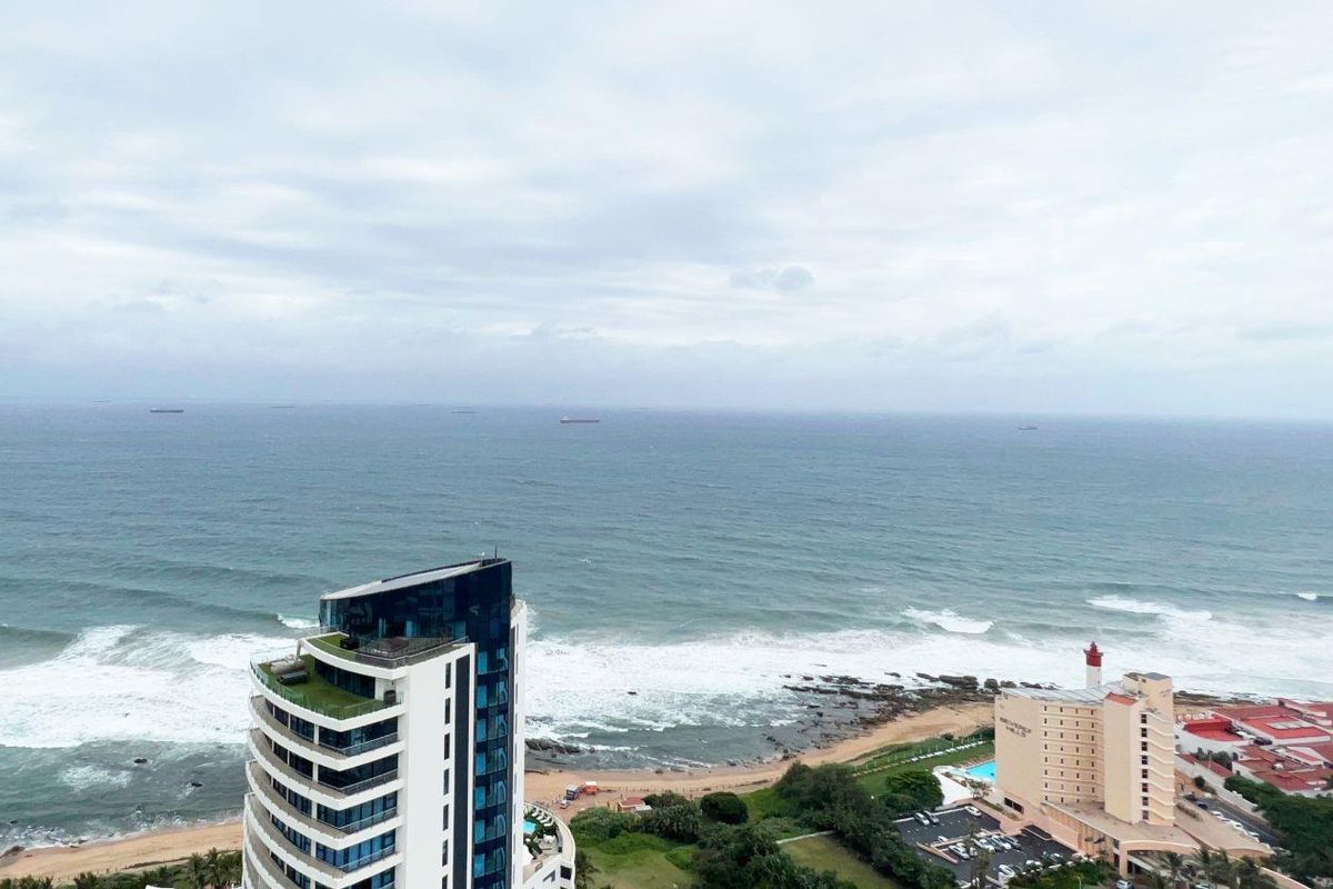 Elevated aerial view showcasing the coastal landscape, ocean horizon, and surrounding high-rise residential architecture.