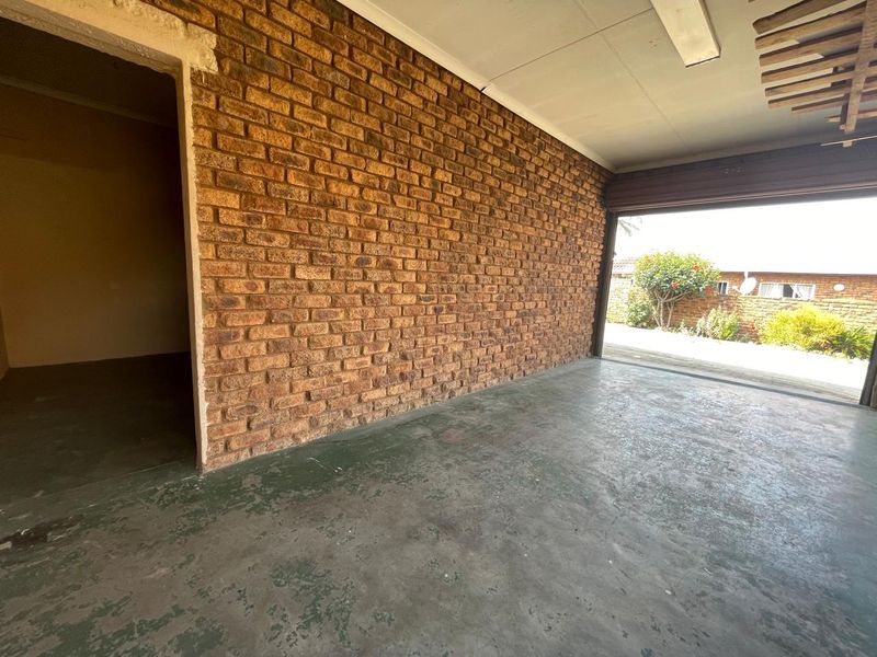 A spacious, empty garage featuring exposed brick walls and a concrete floor, providing ample storage or parking space.