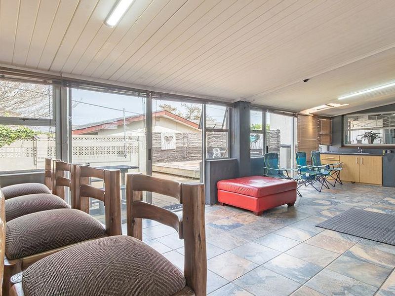Enclosed patio area featuring tiled flooring, built-in cabinetry with a sink, and a pizza oven, providing a versatile space for outdoor entertaining.