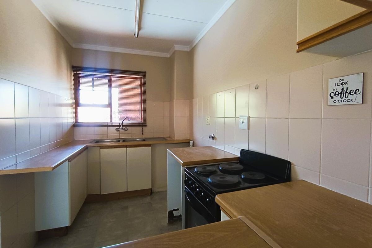 A dated kitchen featuring laminate countertops, tiled splashbacks, a built-in stove, and a double sink with a window view.